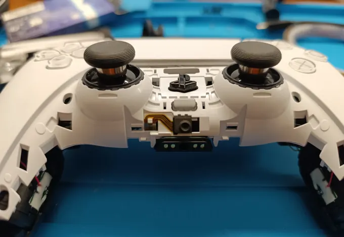 Joypad DualSense aperto sul banco del laboratorio REVEO.